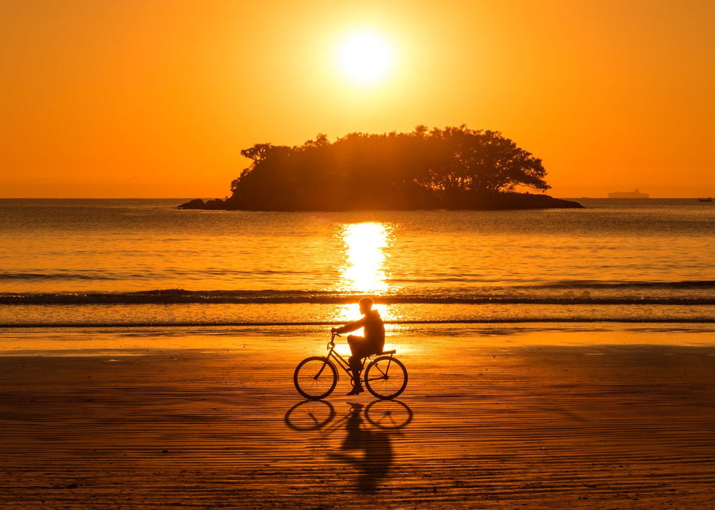 person riding bike at sunset on beach